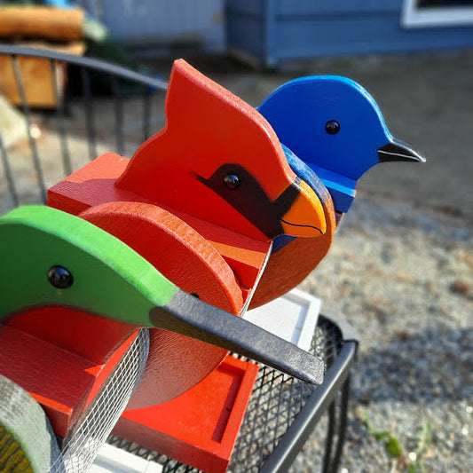 Amish made birdfeeders, blue bird, cardinal and hummingbird. All sitting on a bench together. Handmade and painted with exterior paint.