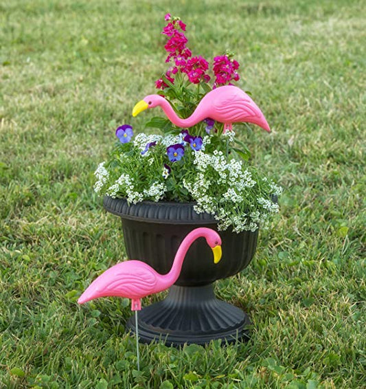 Mini Pink Flamingos - one in a planter, and the other flamingo in the yard in front of the planter.