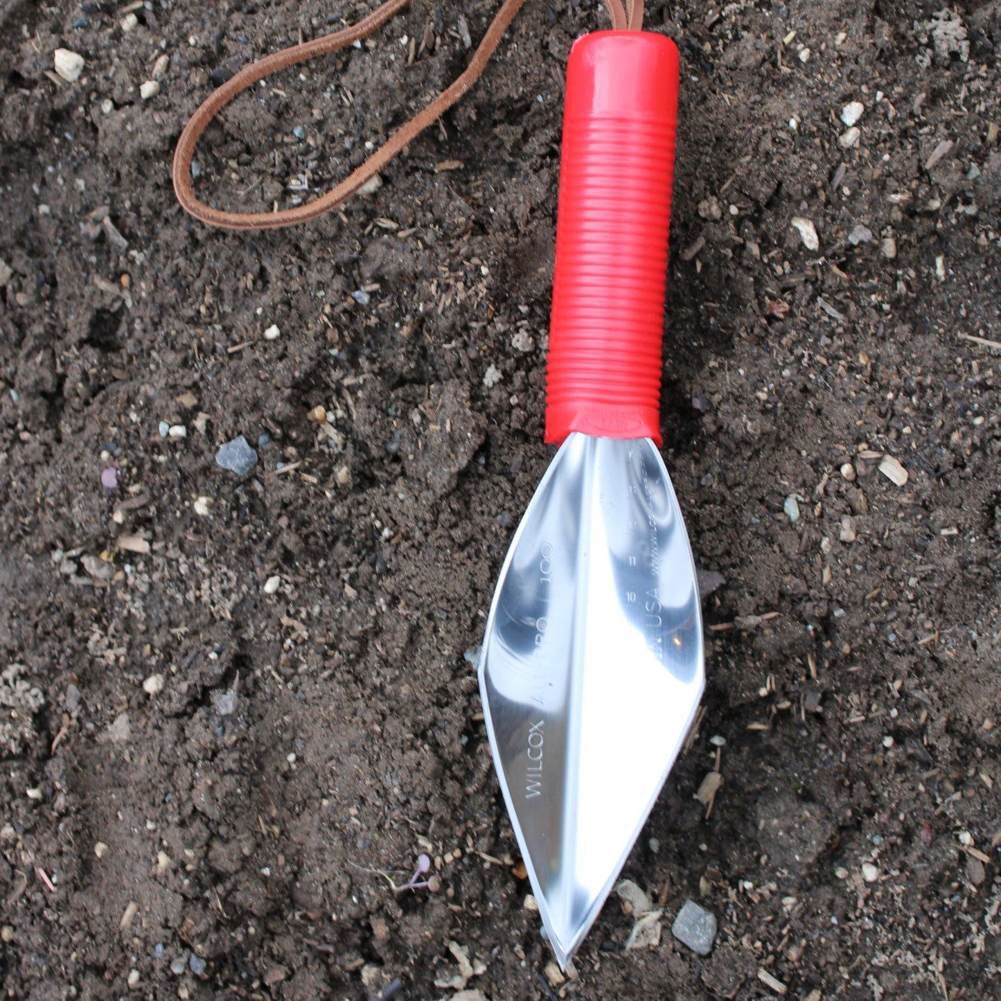 Wilcox stainless steel fine pointed trowel with plastic red handle and leather wrist strap, made in the USA